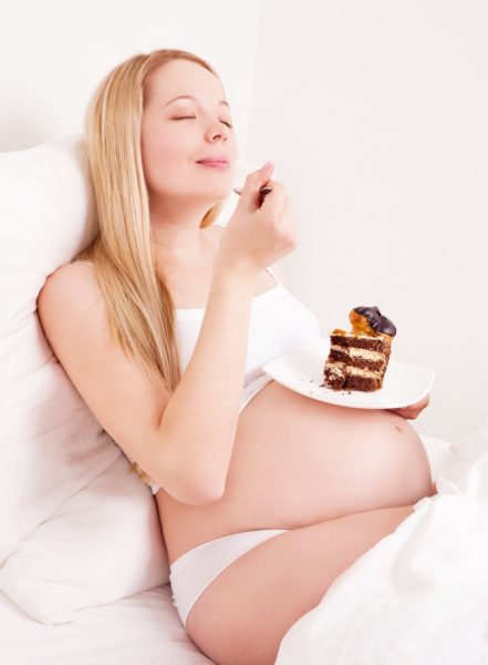 беременная подносит ко рту кусок торта