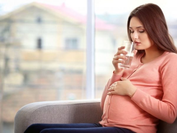 беременная подносит стакан воды ко рту