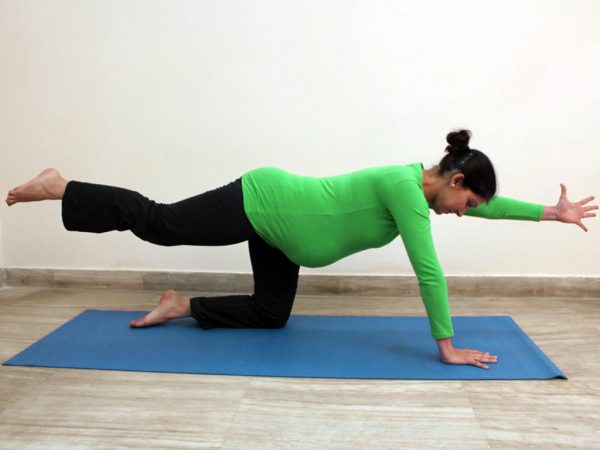 беременная выполняет упражнение из йоги