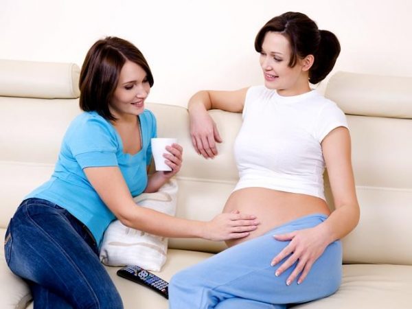 Женщина трогает живот беременной