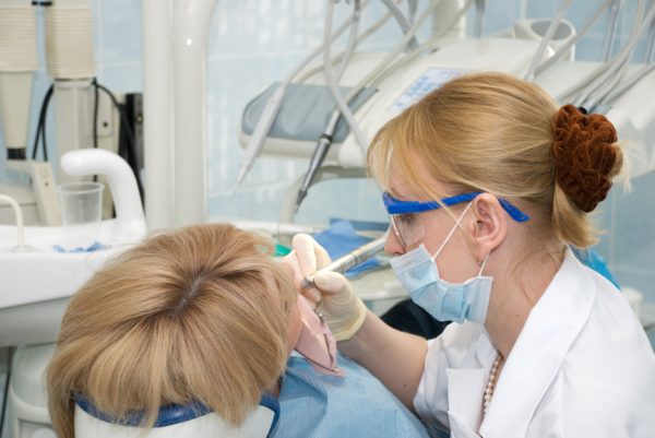 Стоматолог лечит зуб у девушки