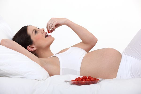 Беременная женщина кушает черешню