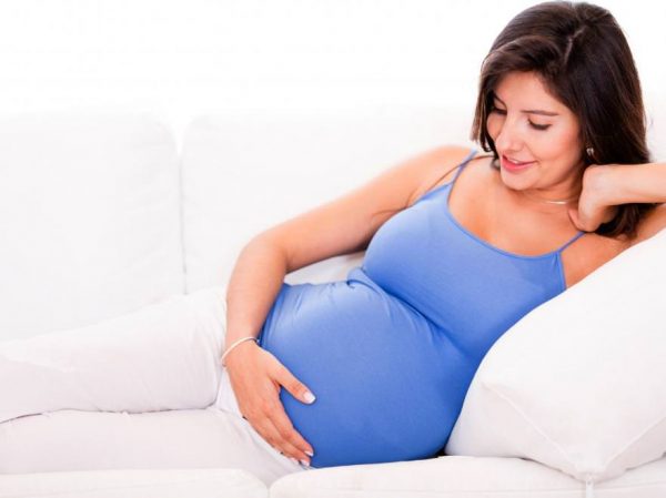 Беременная гладит свой живот и что-то говорит