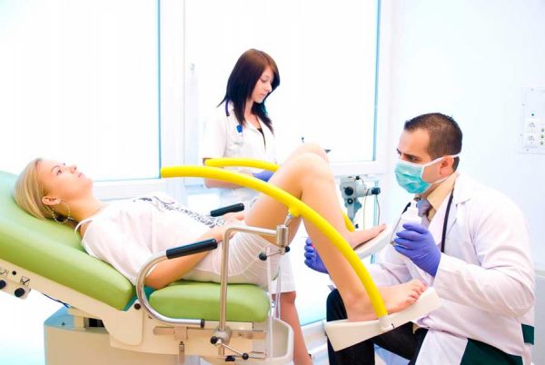 Женщину на гинекологическом кресле осматривает врач