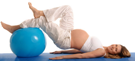 Беременная женщина лежит на спине, положив ноги на большой мяч