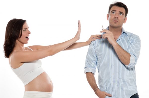 беременная женщина рядом с курящим мужчиной