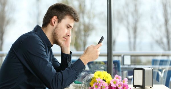 Мужчина сидит в кафе и смотрит в телефон