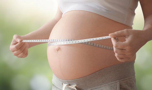 Беременная женщина измеряет живот