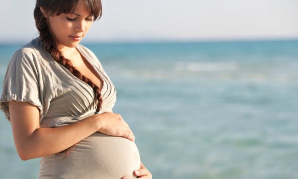 Беременная женщина нежно смотрит на свой большой живот