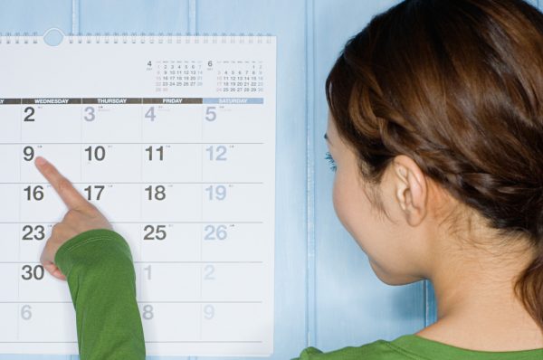 Девушка указывает пальцем на дату в календаре