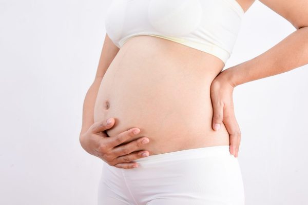 Беременная женщина испытывает боль в пояснице из-за пиелонефрита