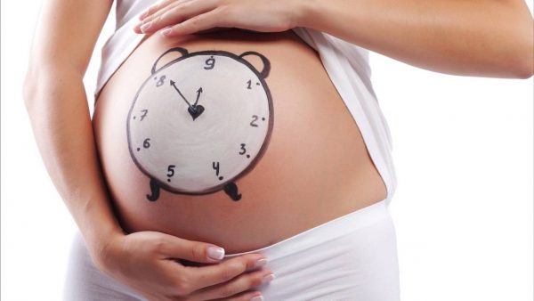 На животе беременной нарисован будильник