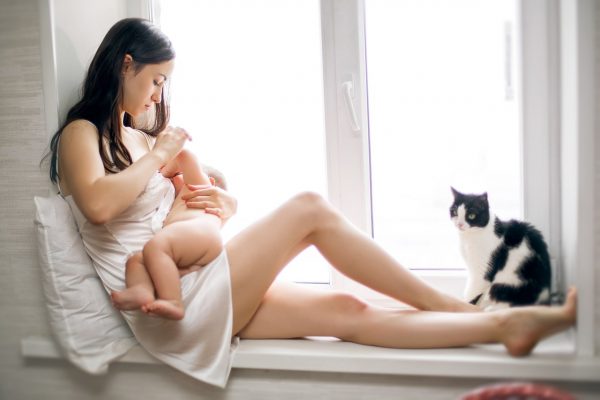 Женщина кормит ребёнка грудью сидя