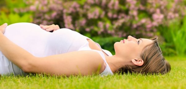 Беременная женщина лежит на траве