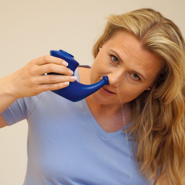 Женщина промывает нос с помощью специального чайника