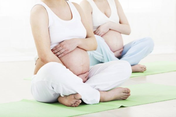 Две беременные женщины сидят в позе лотоса