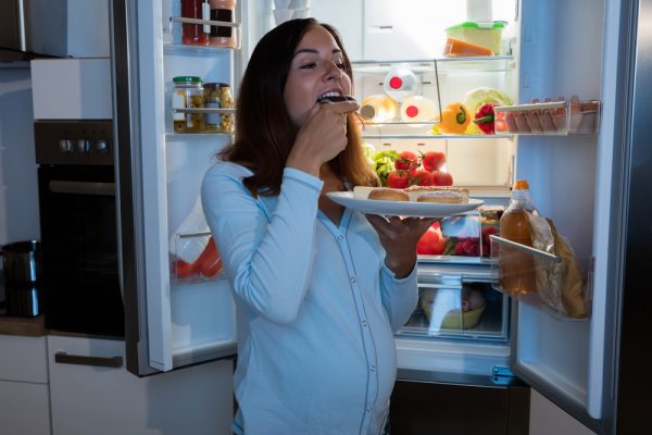беременная ест плюшки у открытого холодильника