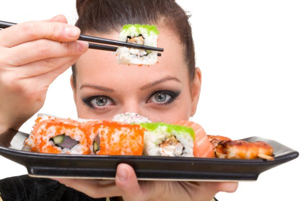 девушка держит в палочках суши