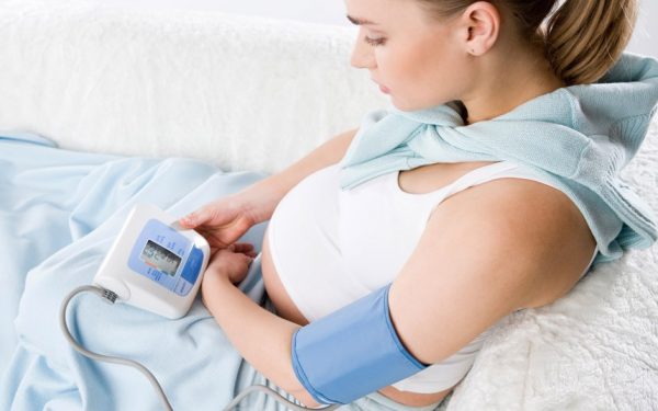 Фотография лежащей беременной женщины с тонометром