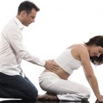 Мужчина делает массаж нижней части спины беременной женщине
