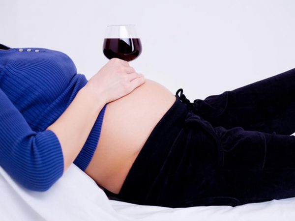 беременная держит бокал вина на животе