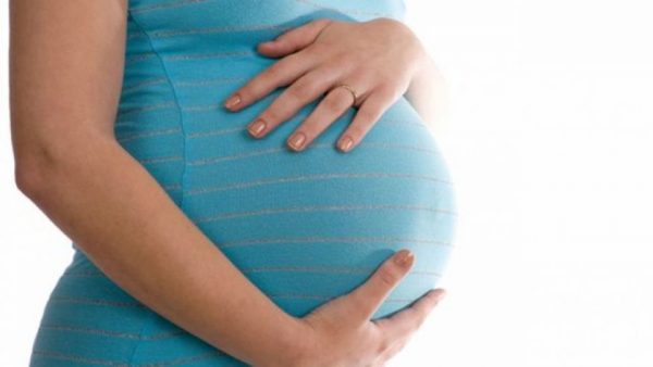 Женщина держится двумя руками за свой беременный живот