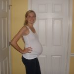 Беременная девушка на 27 неделе стоит у двери
