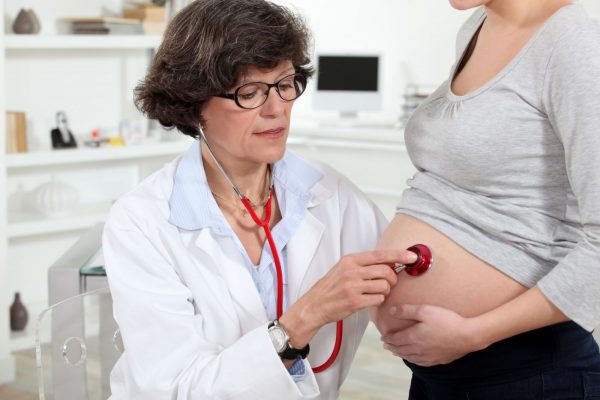 Доктор прослушивает живот беременной