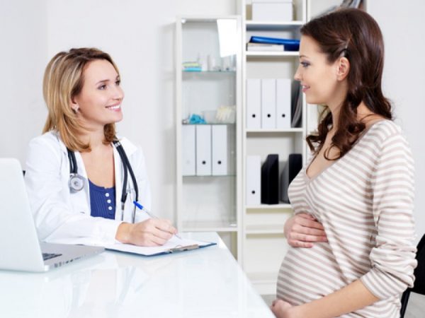 беременная и врач беседуют в кабинете