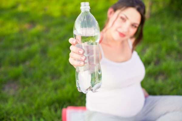 Беременная женщина держит бутылку с водой