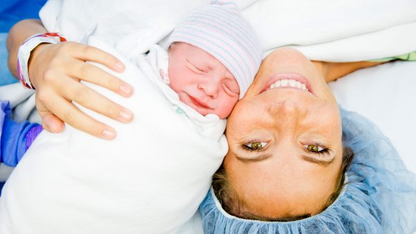 Женщина после родов с новорождённым лежат лицом к лицу