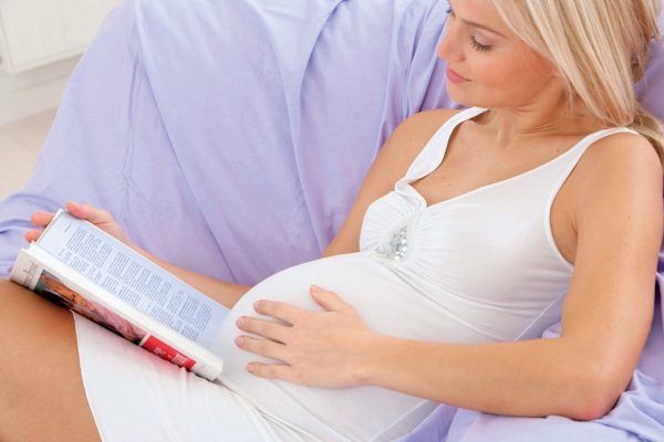Беременная женщина читает книгу