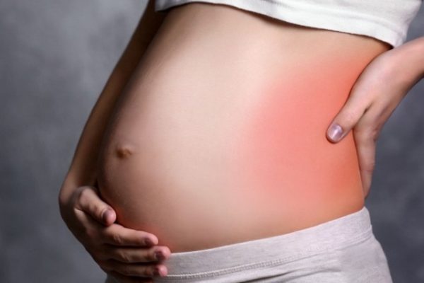 Беременная женщина держится за поясницу слева, воспалённая область обозначена покраснением