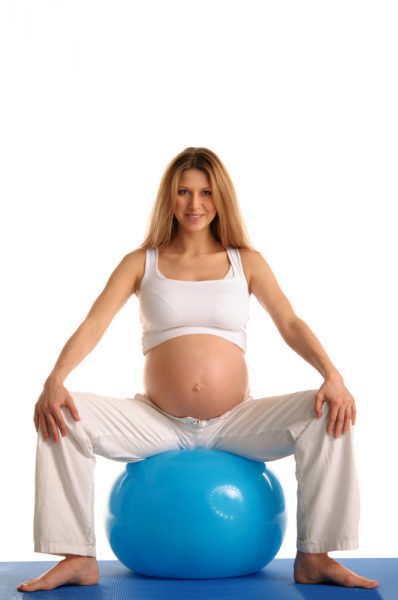 Беременная женщина сидит на фитболе