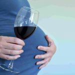 Беременная держит бокал с вином