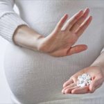 Беременная держит в руках таблетки