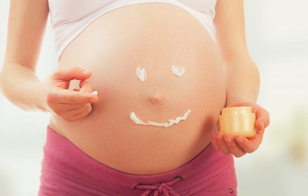 Смайлик, нарисованный кремом, на животе беременной женщины