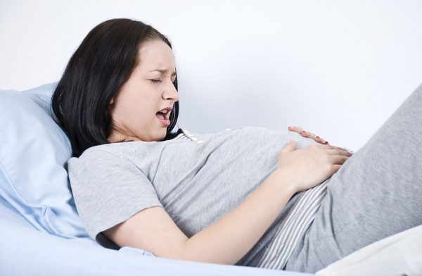 беременная держится за живот с выражением муки на лице