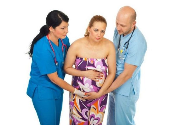 Беременную женщину придерживают двое врачей