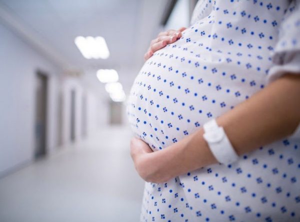 Живот беременной женщины в больничной сорочке